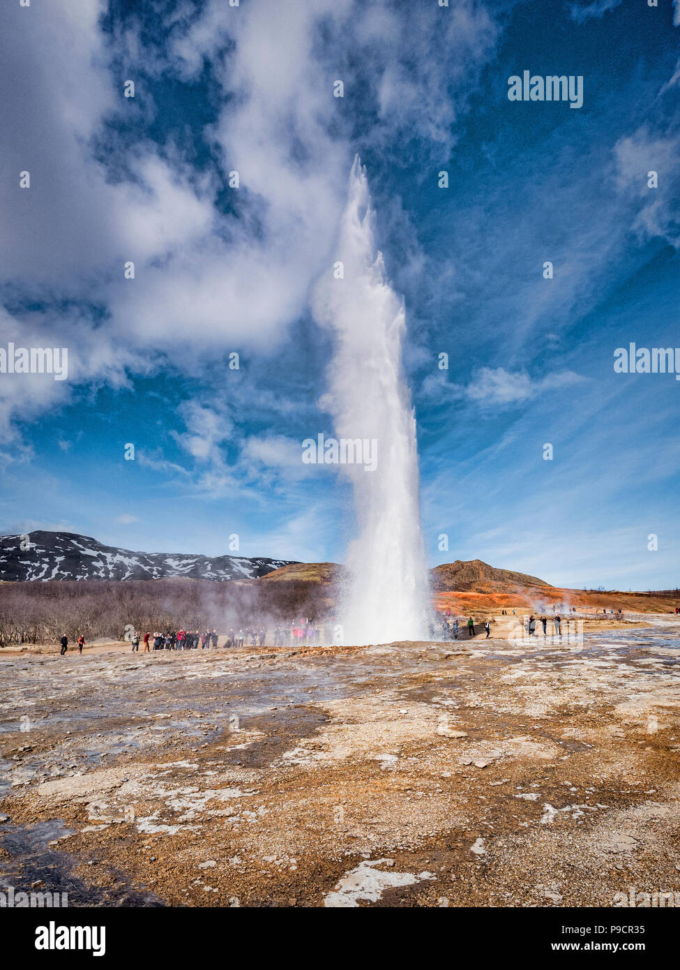 20 April 2018: Geysir, Iceland - Strokkur hot spring in the Geysir geothermal area erupts, watched by a crowd of visitors. This is one of the major at Stock Photo