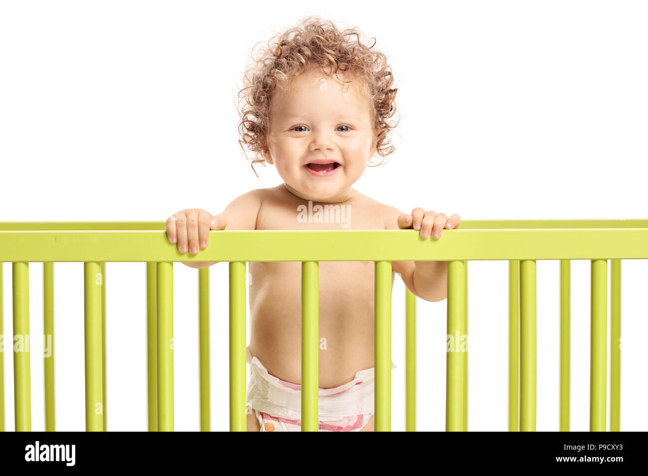 Baby boy in a cot bed looking at the camera and smiling isolated on white background Stock Photo