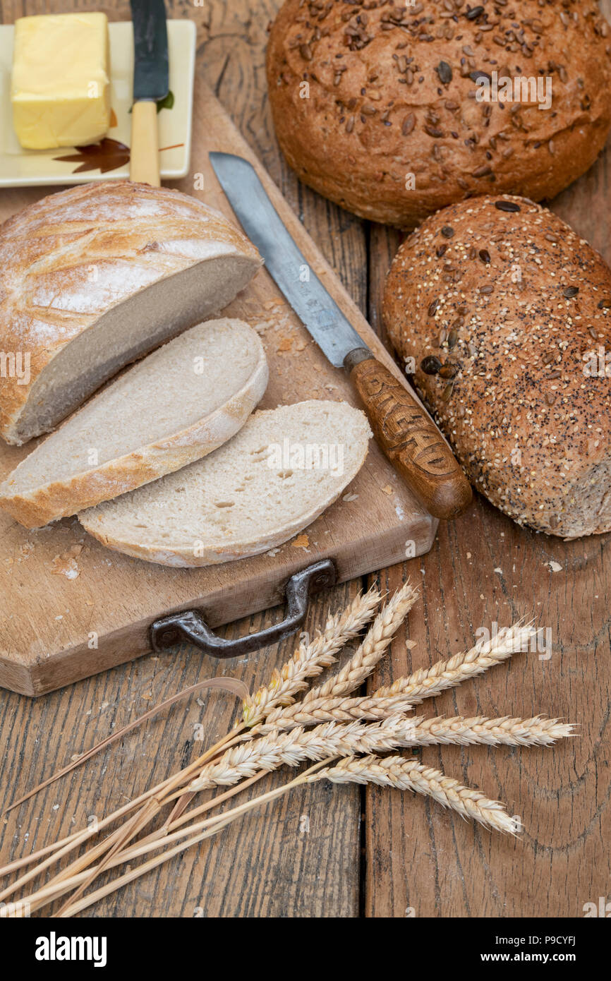 Sliced White bread with seeded loaves on a bread board with wheat and a bread knife. UK Stock Photo