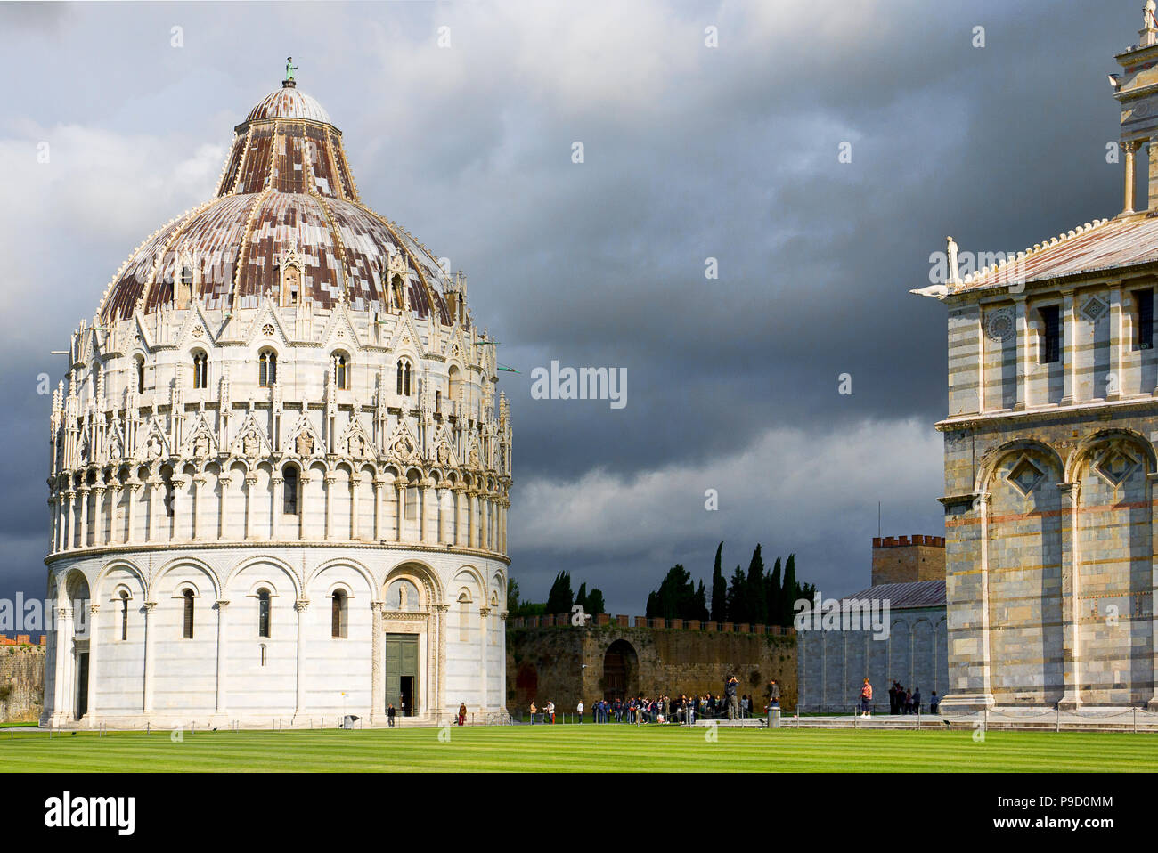 The Pisa Baptistery of St. John and Pisa Cathedral. Grand marble-striped cathedral known for its ornate Romanesque bronze doors & carved 1300s pulpit. Stock Photo