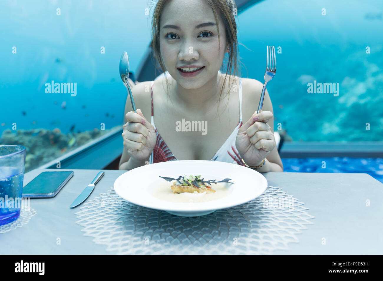 Asian beautiful woman dinner on undersea world background,  underwater restaurants in Maldives. Stock Photo