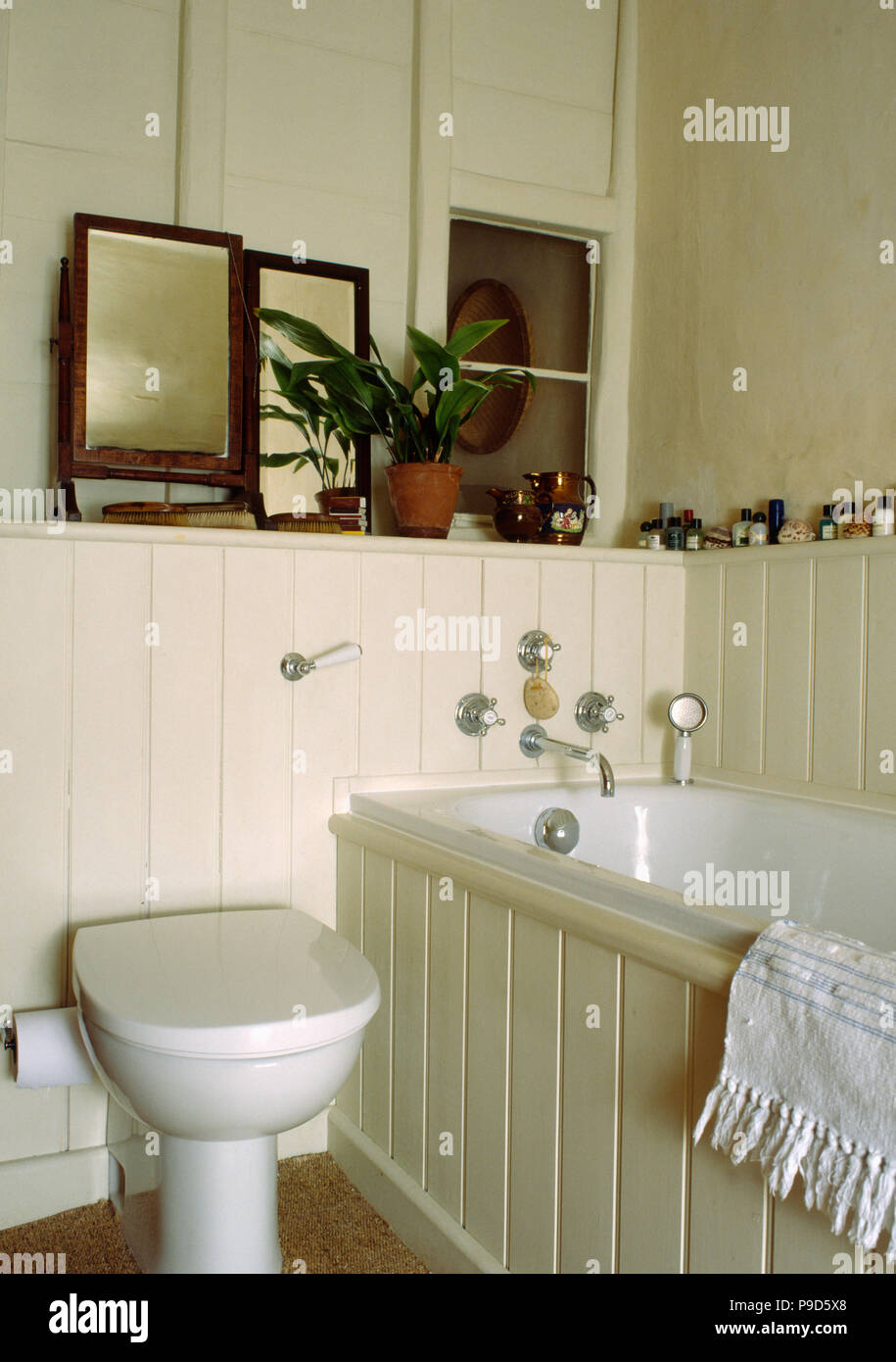 Mirrors on shelf in cream panelled cottage bathroom Stock Photo