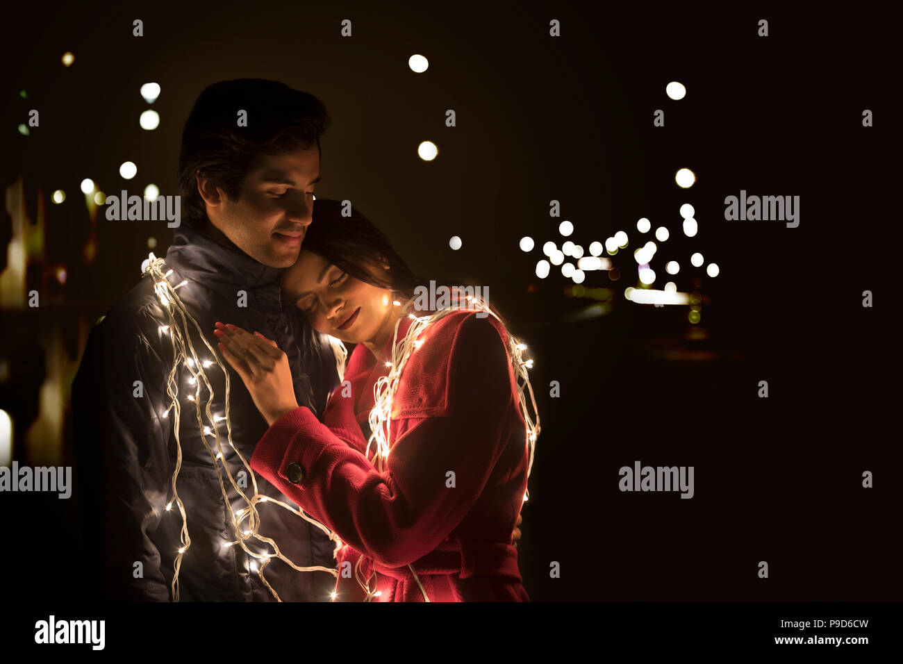 Romantic young couple wrapped in decorative lights Stock Photo