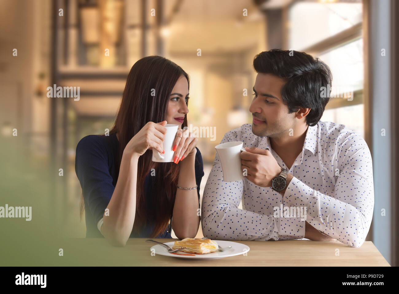 Happy young couple having hot drink at restaurant table Stock Photo - Alamy