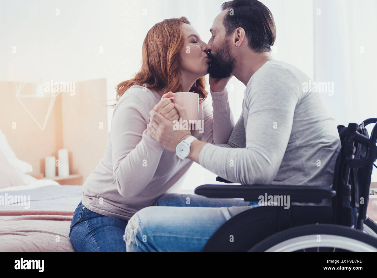 Disabled man sitting in a wheelchair and kissing his beloved woman