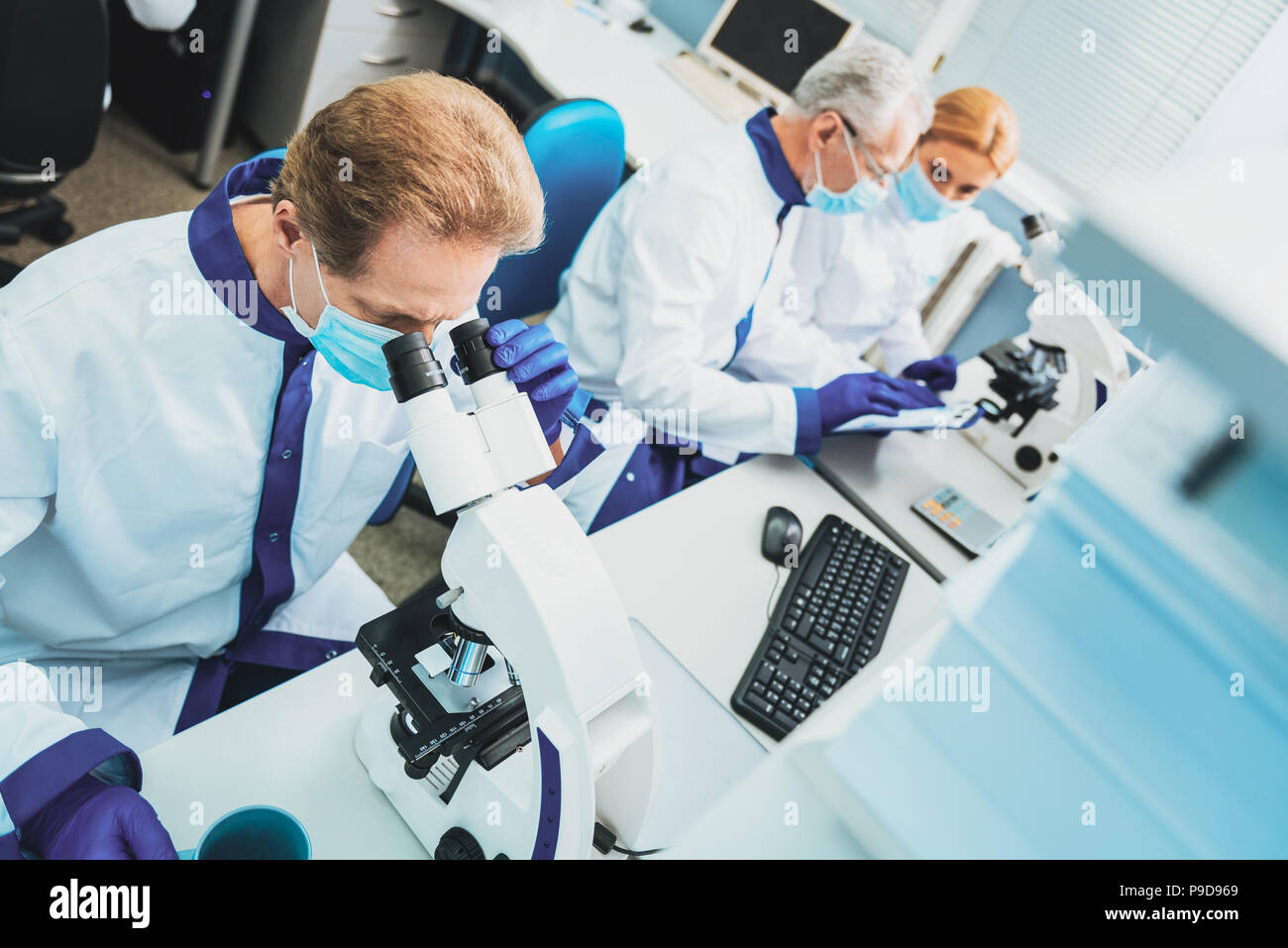 Concentrated researcher using microscope while working Stock Photo