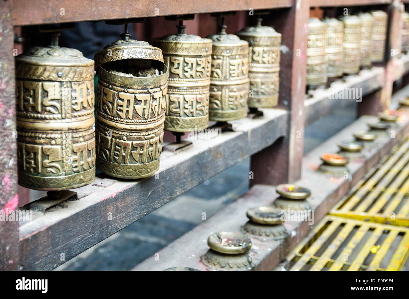 Prayer wheels and butter lamps in the courtyard of Kwa Bahal or Golden Temple in Patan, Nepal Stock Photo