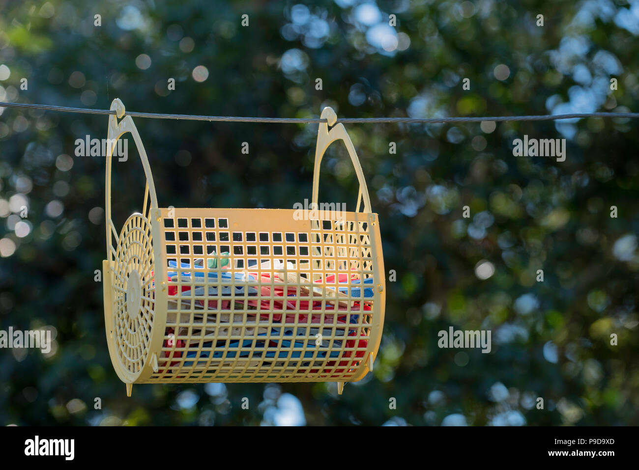 A plastic clothes basket hanging from a metal line as part of a Hills Hoist Clothes line in Australia Stock Photo