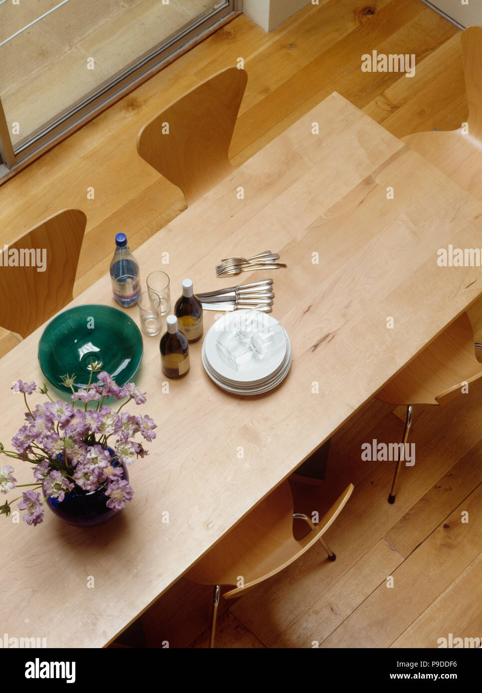 Aerial view of plates and cutlery on modern wooden table in dining room