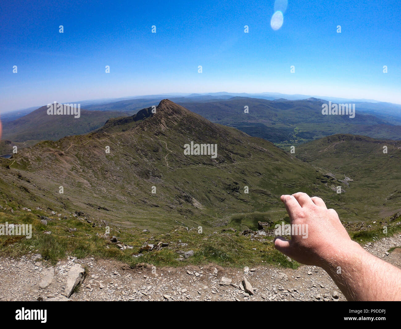 A mans hand reaches out over the views from the summit of Mount Snowdon