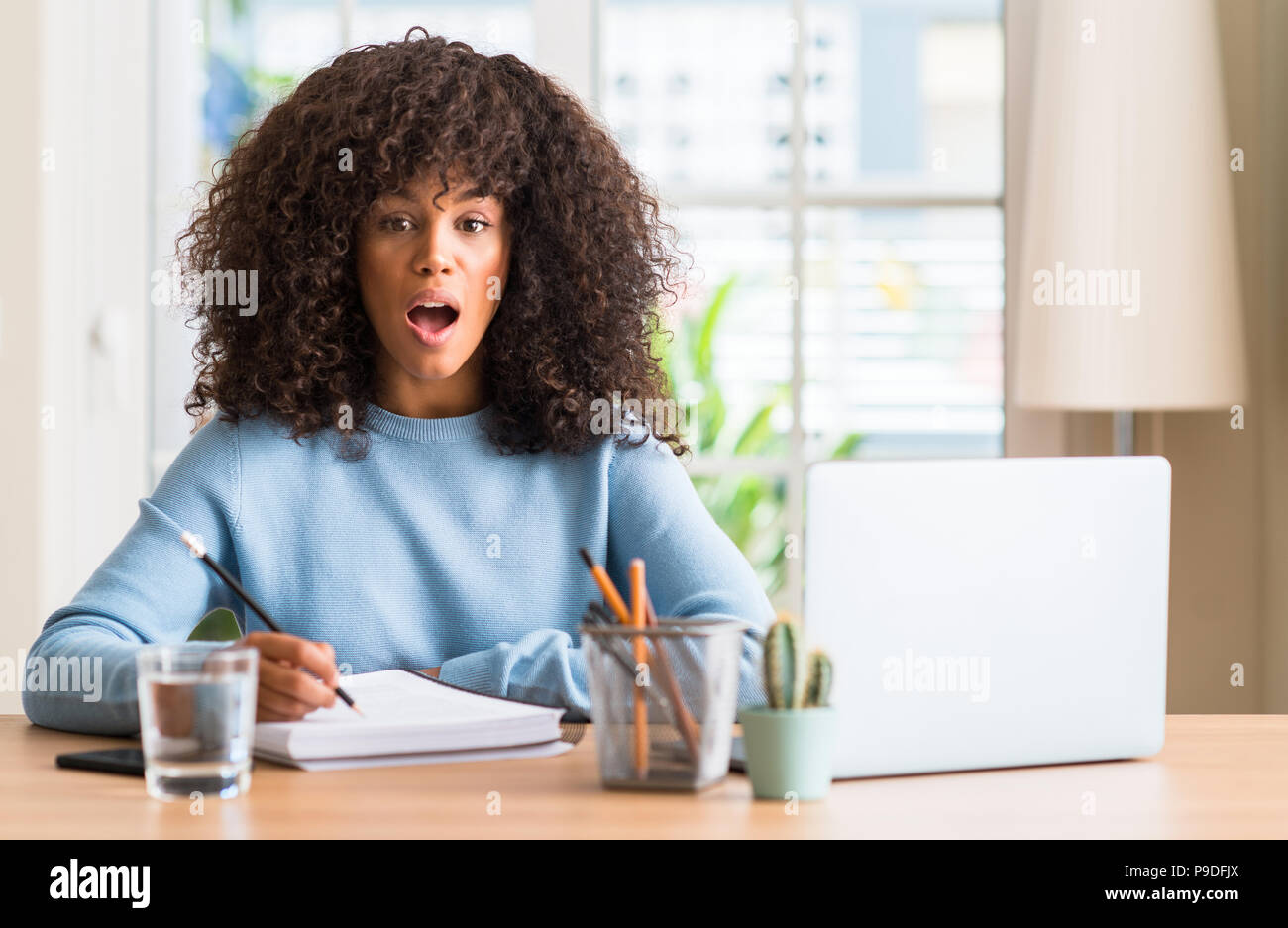 African american woman studying at home using a computer laptop scared ...