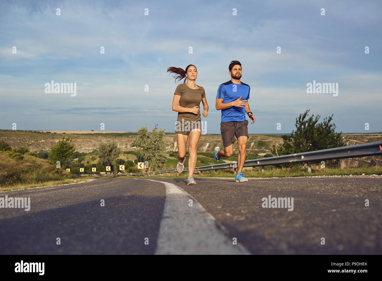 A guy and a girl jog along the road in nature.  Stock Photo