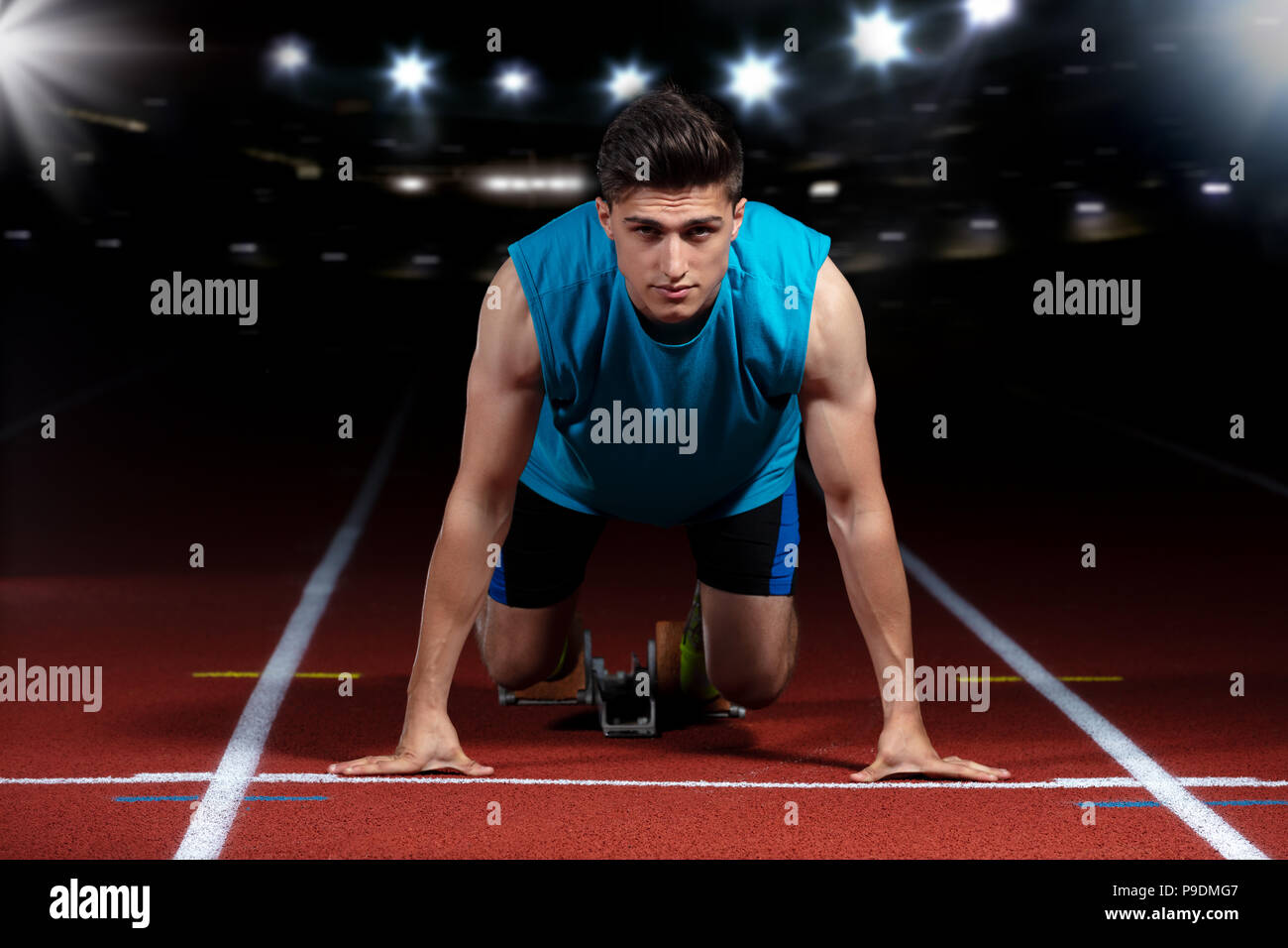 Sprinter leaving starting blocks on the running track in front of big