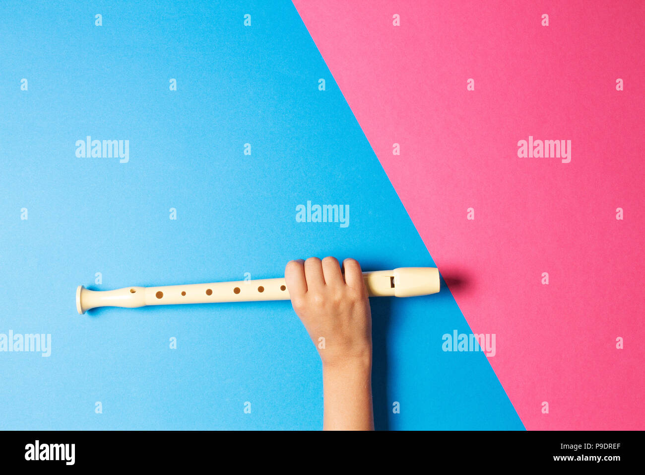 Kid hand with flute on colorful background. Stock Photo