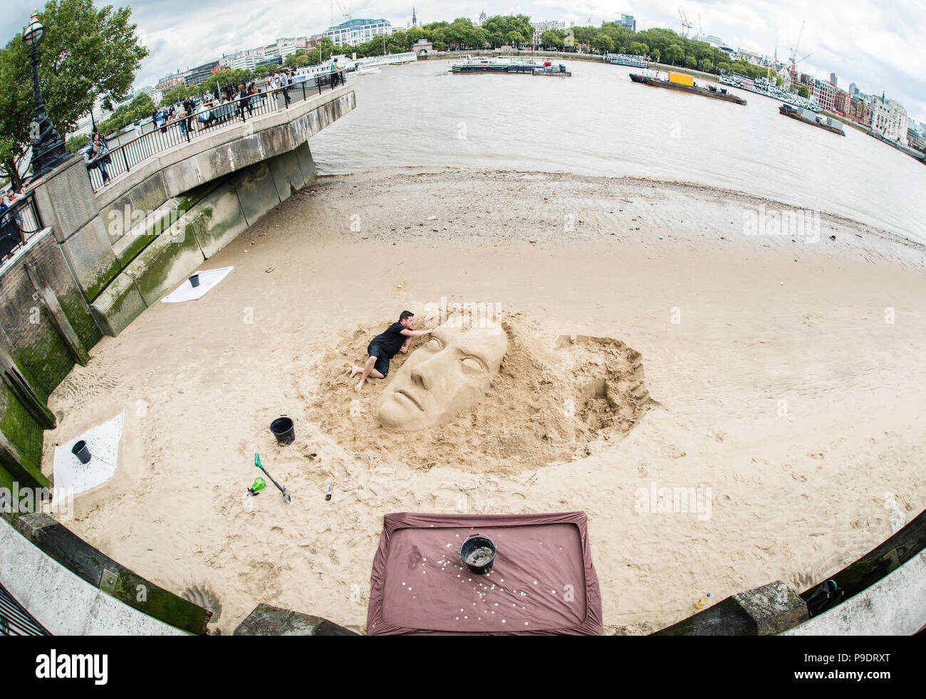 Street photography image of a male artist doing a sand sculpture on the banks of the River Thames in London Stock Photo