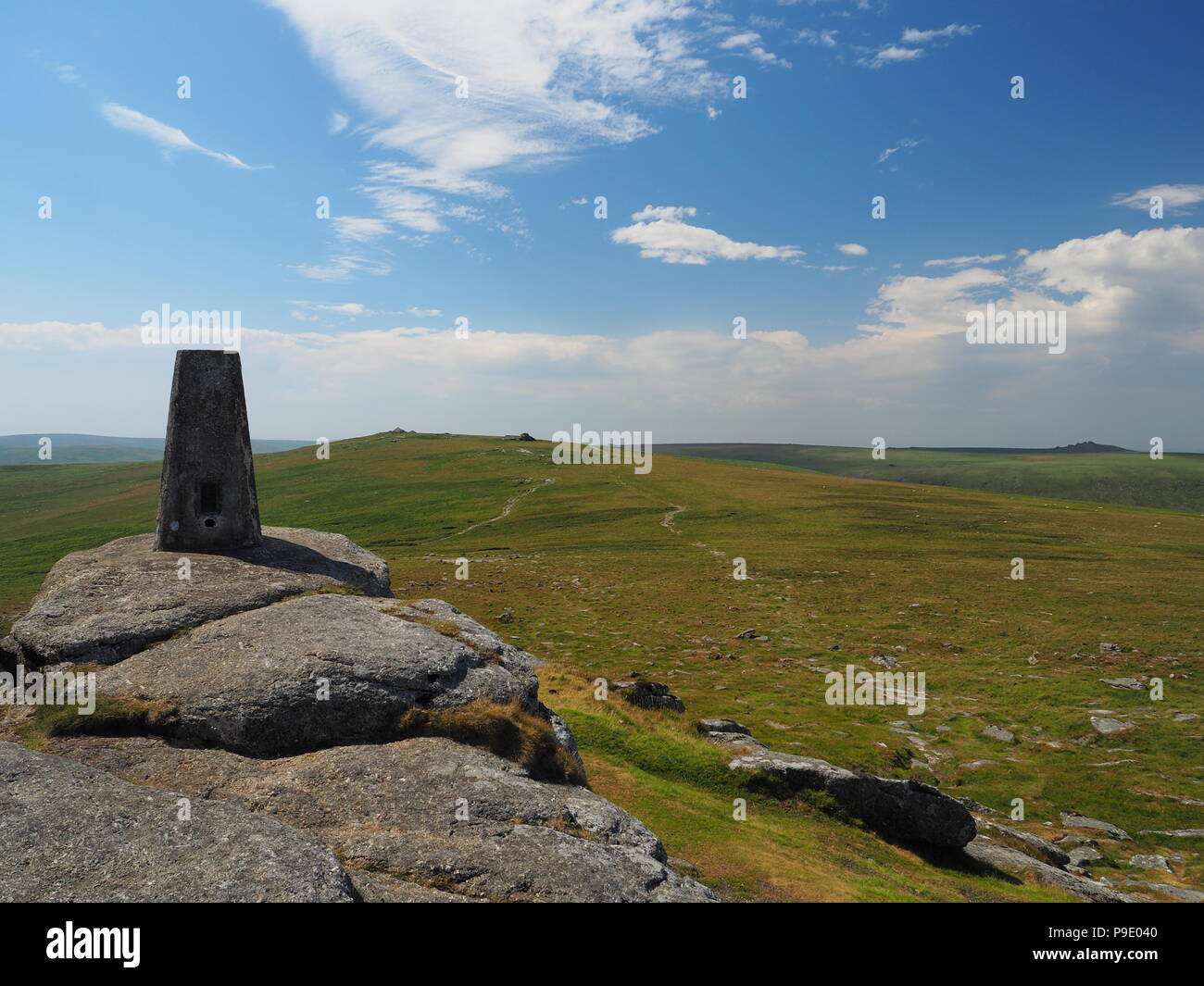 Triangulation pillar on Yes Tor looking to High Willhays with white clouds in a blue sky, Dartmoor Stock Photo