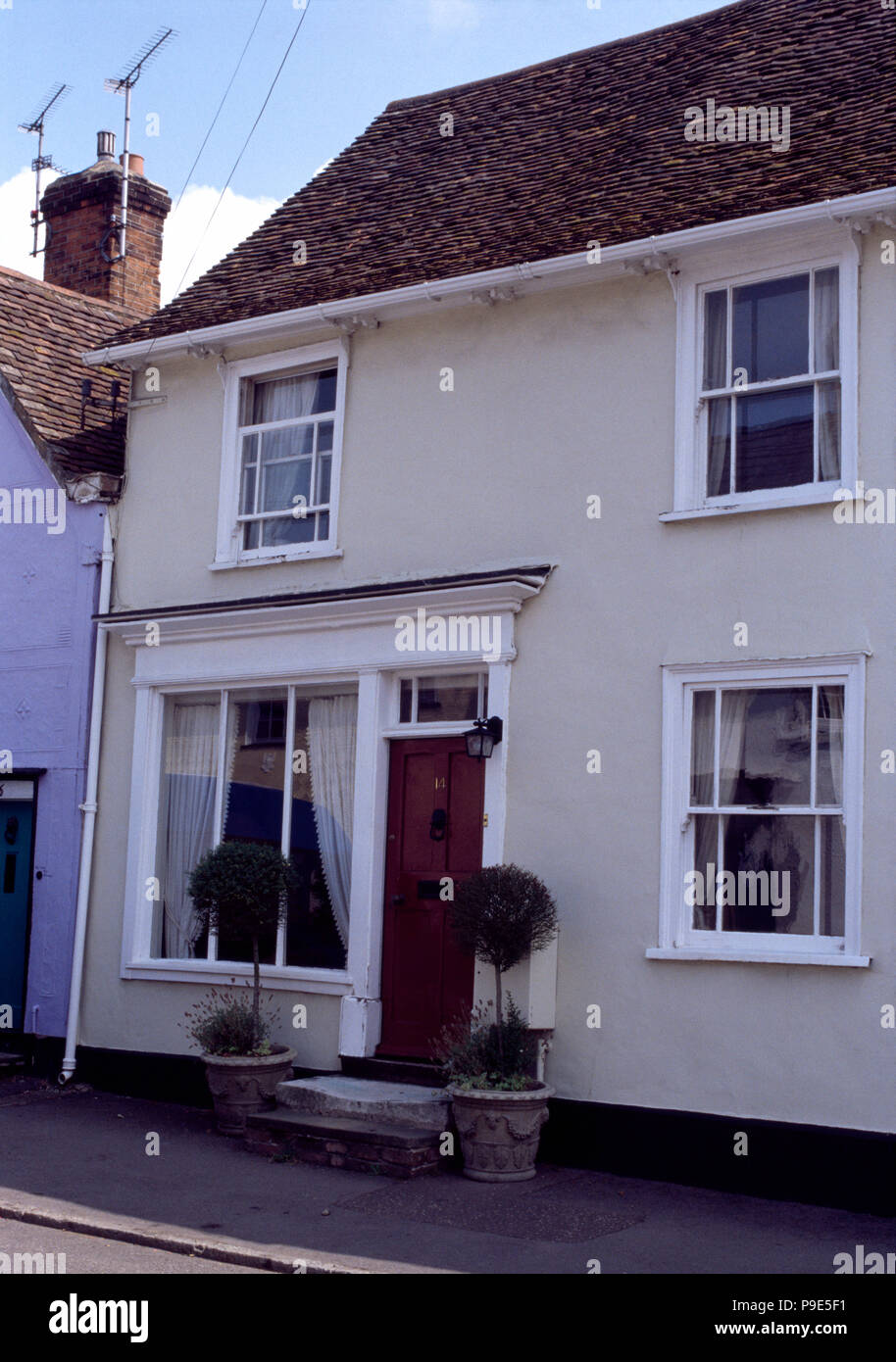 Clipped bay trees in pots on either side of front door of traditional