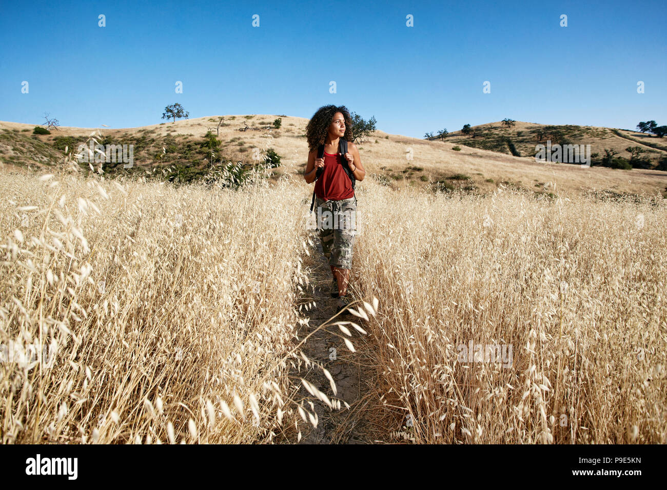 Young woman with curly brown hair hiking in urban park Stock Photo - Alamy