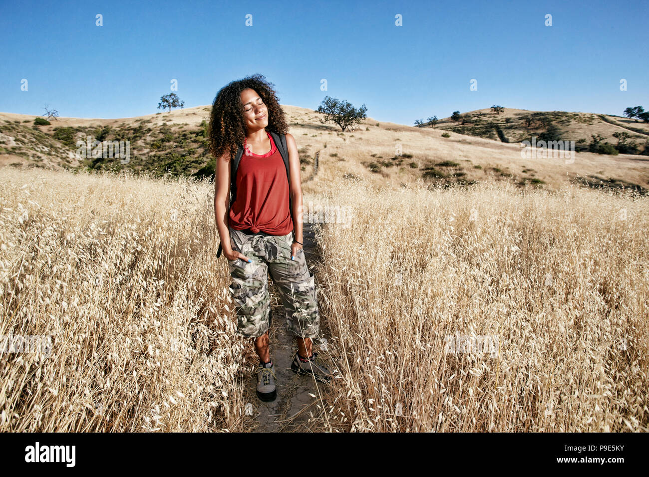 Young woman with curly brown hair hiking in urban park Stock Photo - Alamy