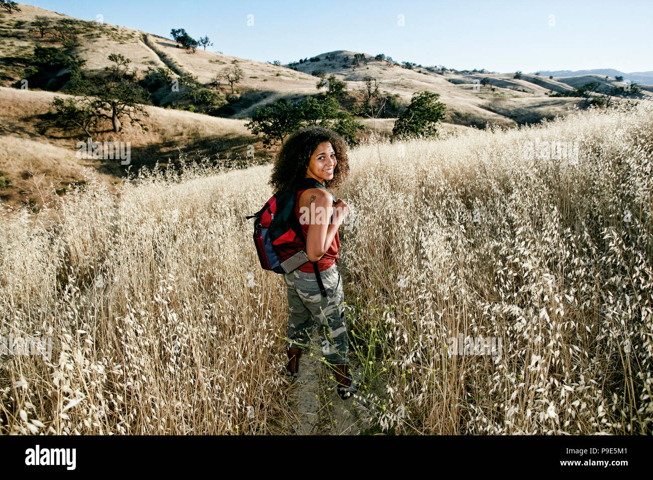Young woman with curly brown hair hiking in urban park Stock Photo - Alamy