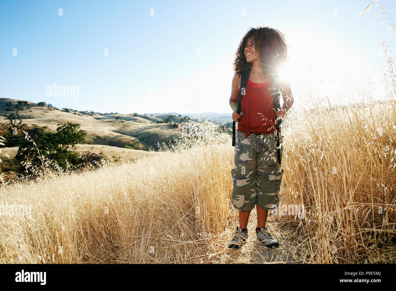 Young woman with curly brown hair hiking in urban park Stock Photo - Alamy