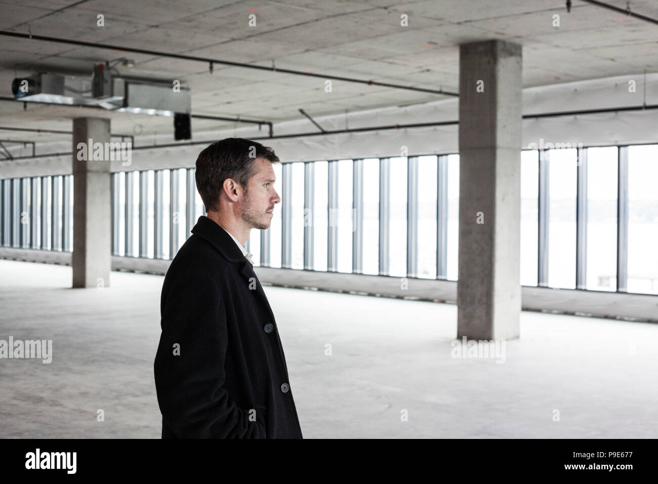 A man lookin around an empty building, raw office space, potential business premises, architect or planner. Stock Photo
