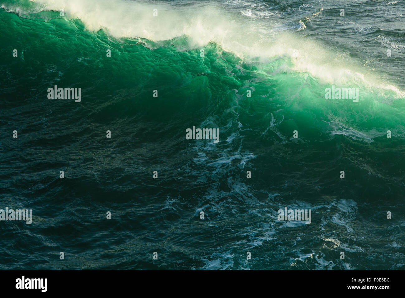 Detail of crashing waves, surf and crest, windblown mist curling from the white water, and deep green ocean water. Stock Photo