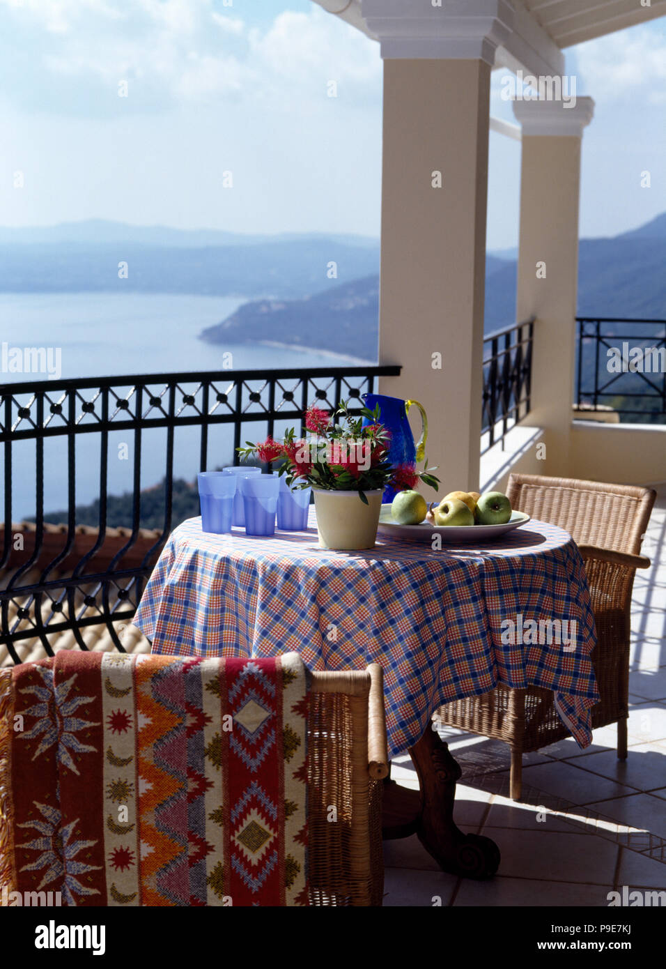 Blue glass jug on table with checked cloth on balcony of a villa overlooking the ocean Stock Photo