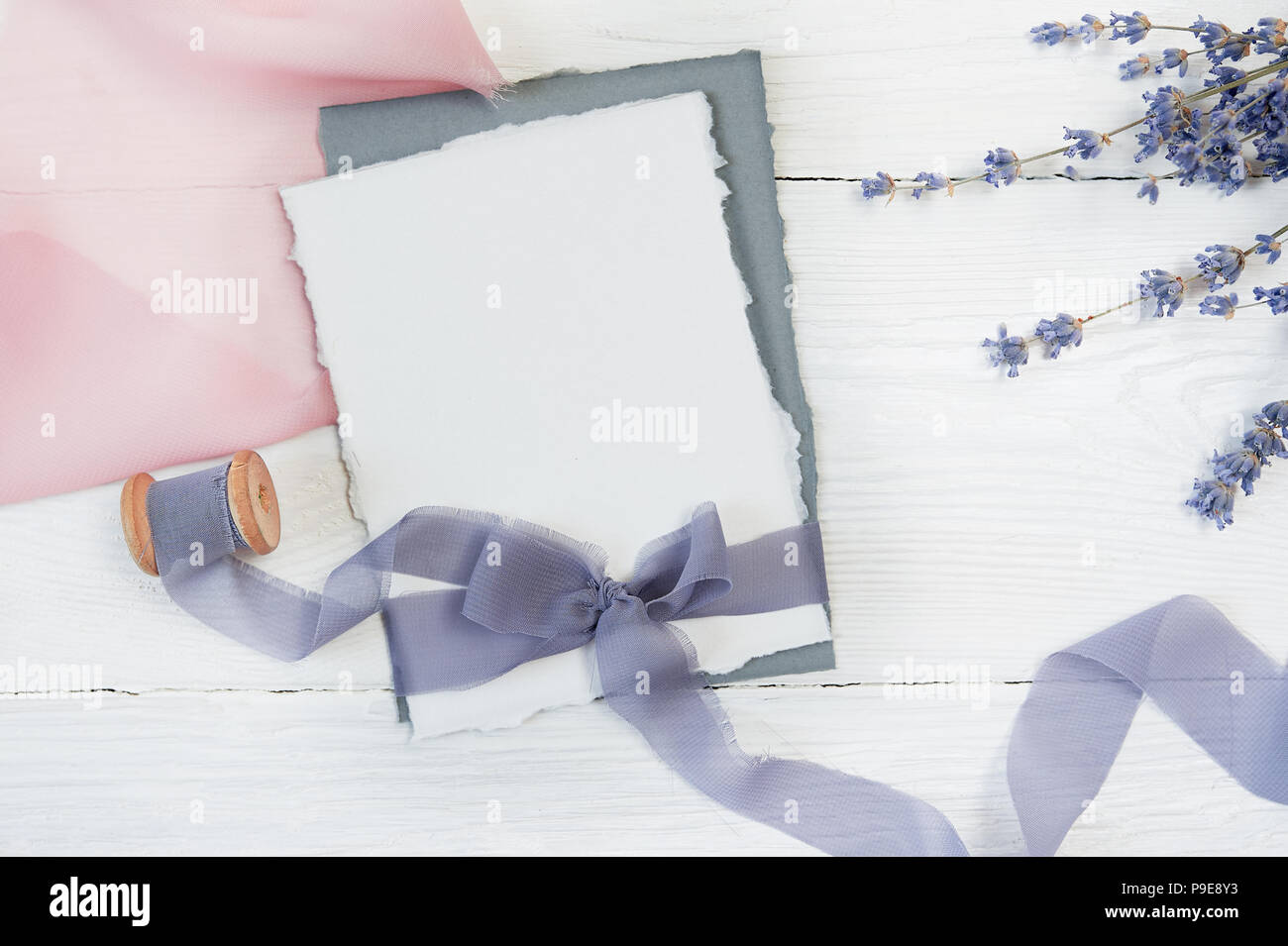 White blank card ribbon bow on a background of pink and blue fabric ...