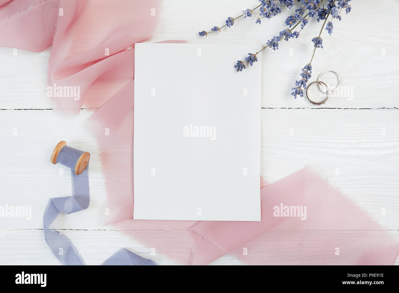 White blank card ribbon with two wedding rings on a background of pink ...