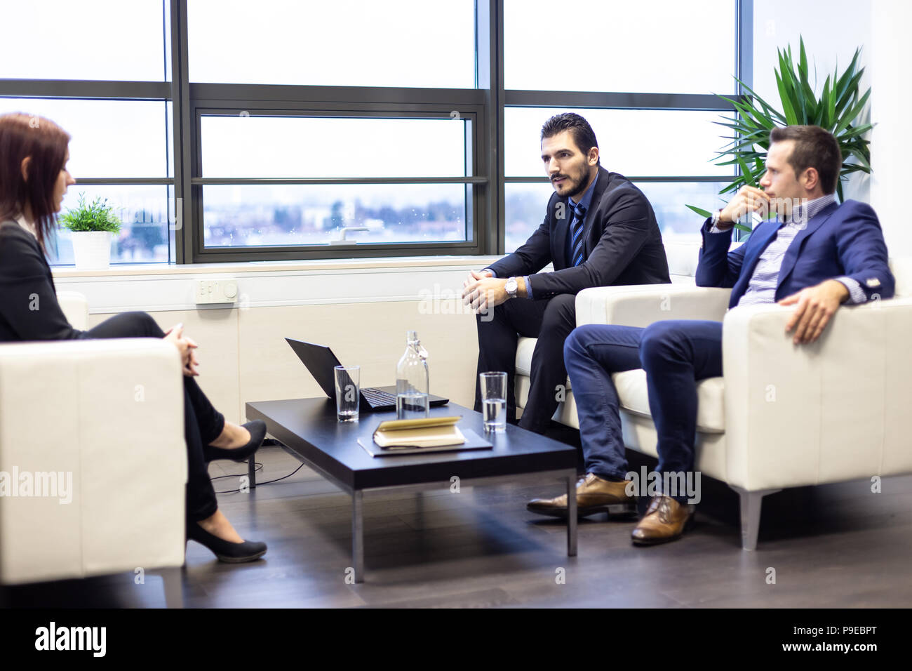 Businessmen interviewing female candidate for job in modern corporate office. Stock Photo