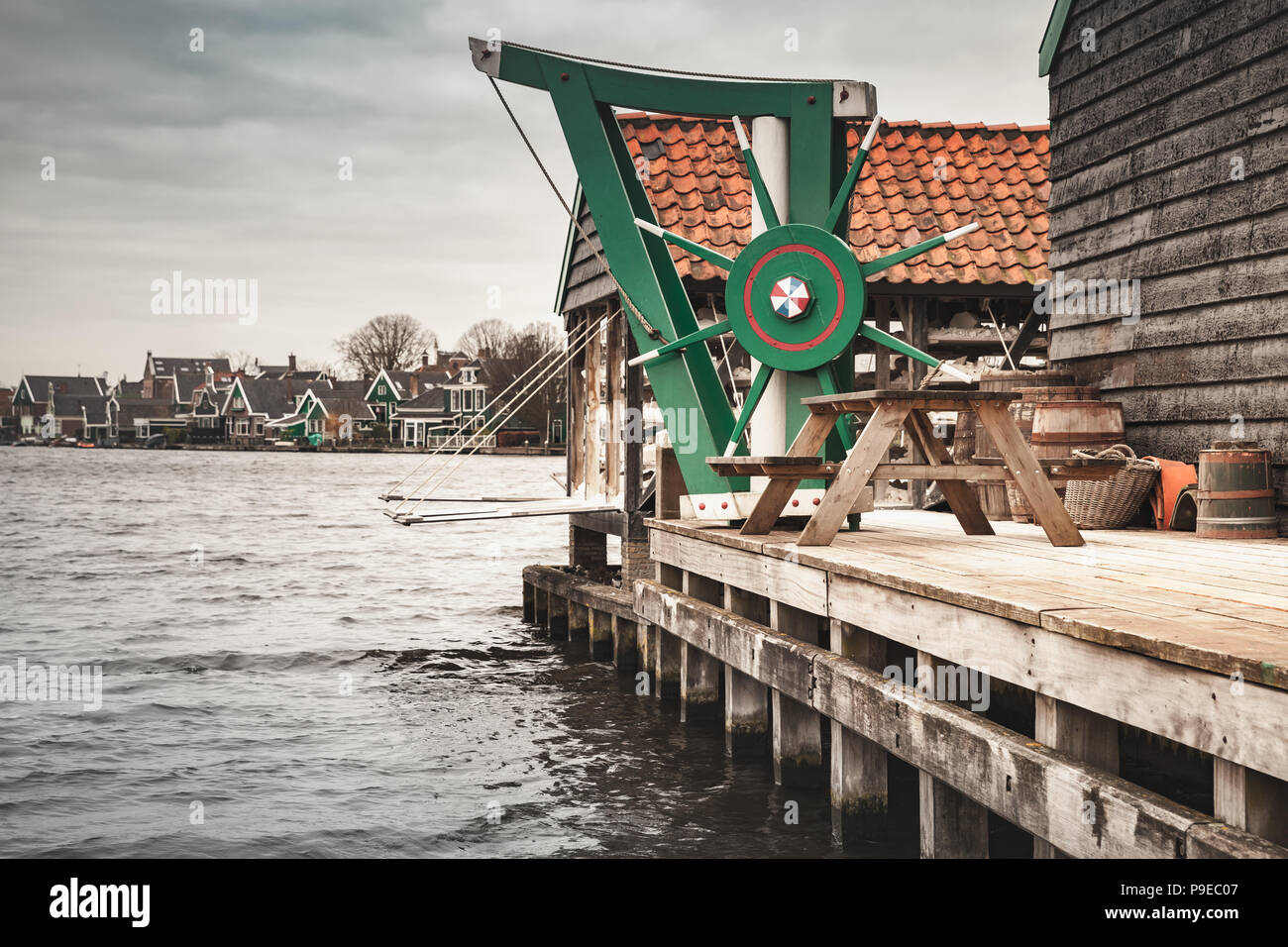 Vintage wooden crane mounted near windmill. Zaanse Schans town, popular tourist attractions of the Netherlands. Suburb of Amsterdam Stock Photo