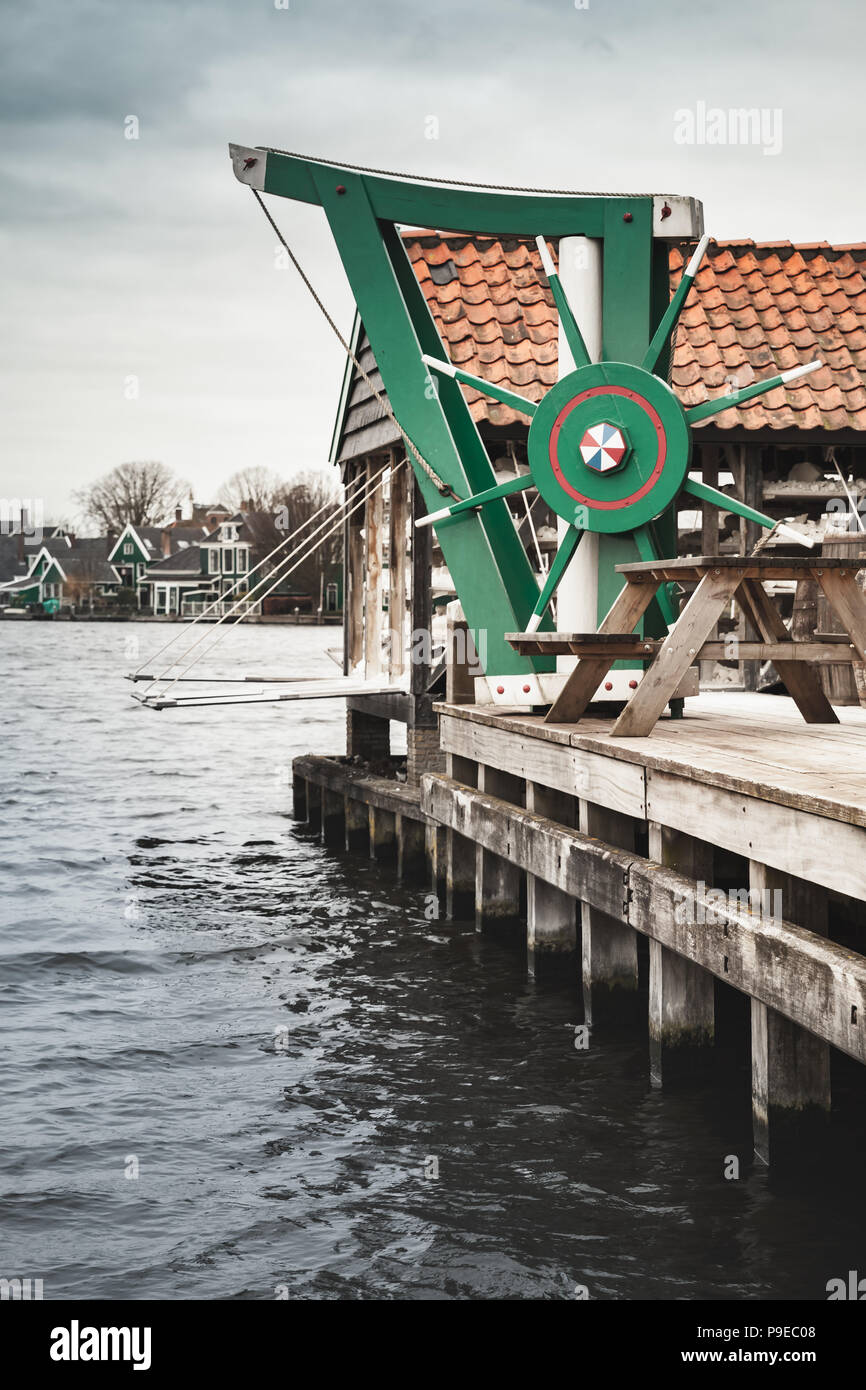 Vintage wooden manual crane mounted near windmill. Zaanse Schans town, popular tourist attractions of the Netherlands. Suburb of Amsterdam Stock Photo