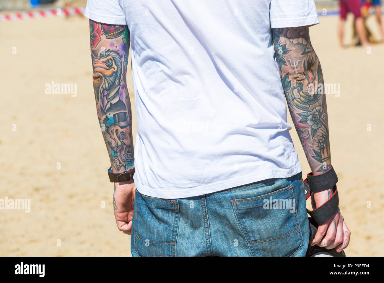 Man with tattoos on arm at the beach at Branksome Dene, Poole, Dorset UK in July Stock Photo