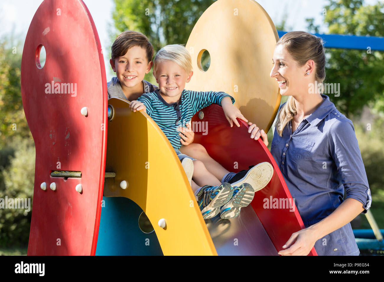 Family playing on adventure playground, children chuting chute Stock Photo
