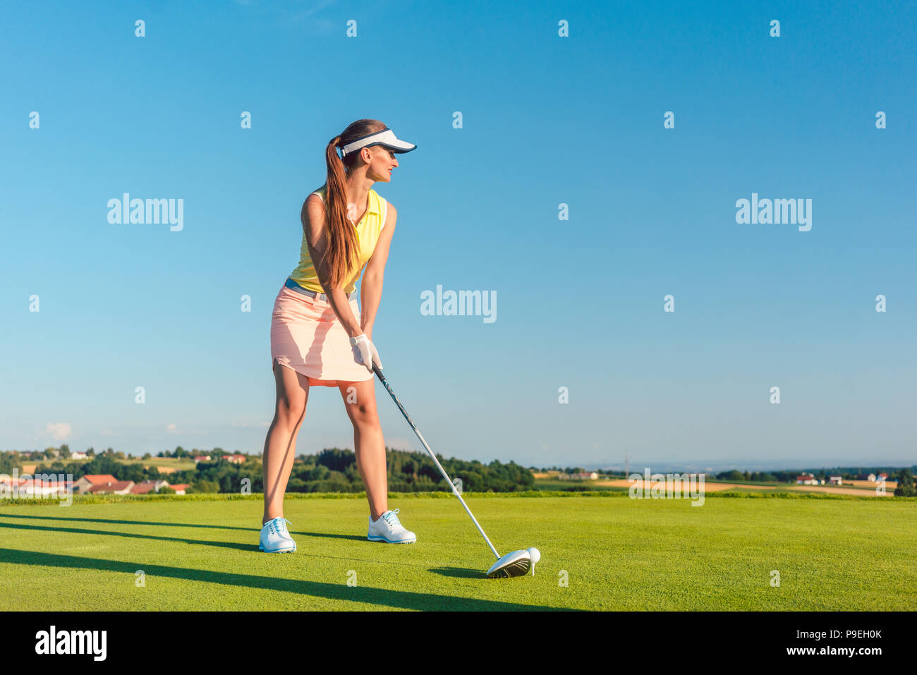 Professional female golf player smiling while swinging a driver club Stock Photo