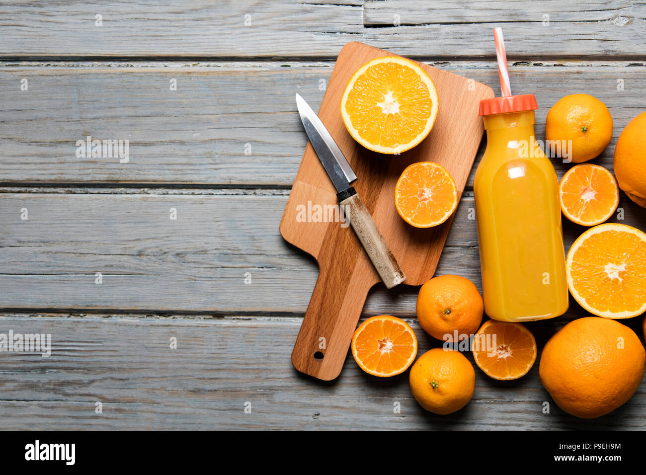 Fresh orange juice in a bottle with oranges on a rustic wooden