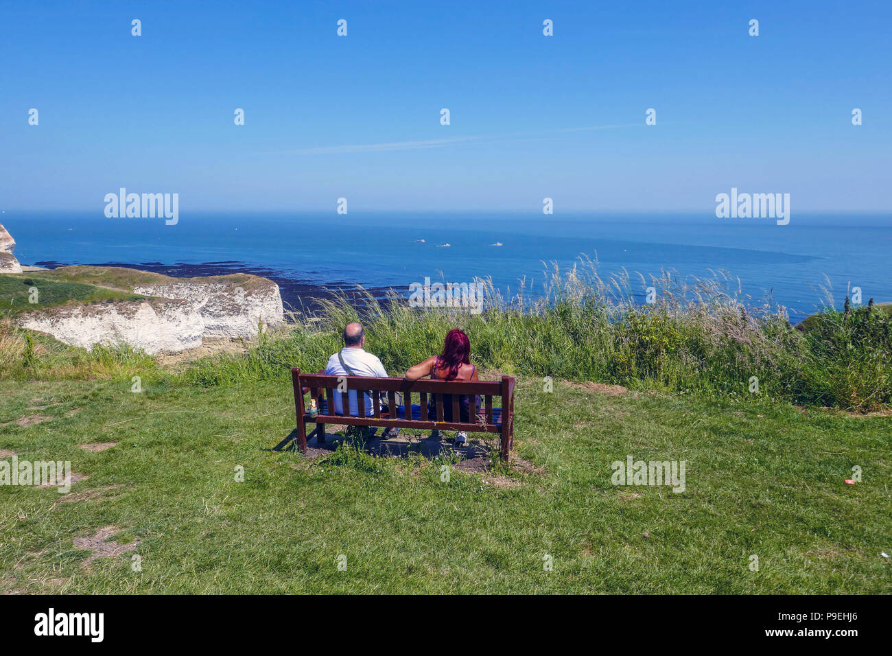 Couple sat on bench with view over the sea, summer weather at Flamborough Head, Easy Yorkshire Stock Photo