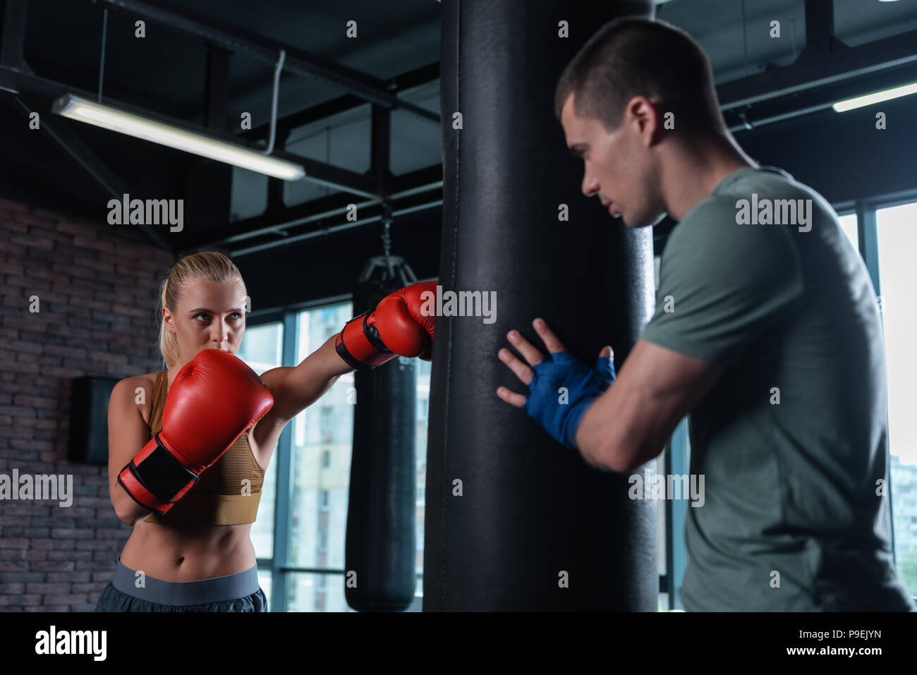 Blonde-haired female boxer coming to gym for working with trainer Stock Photo