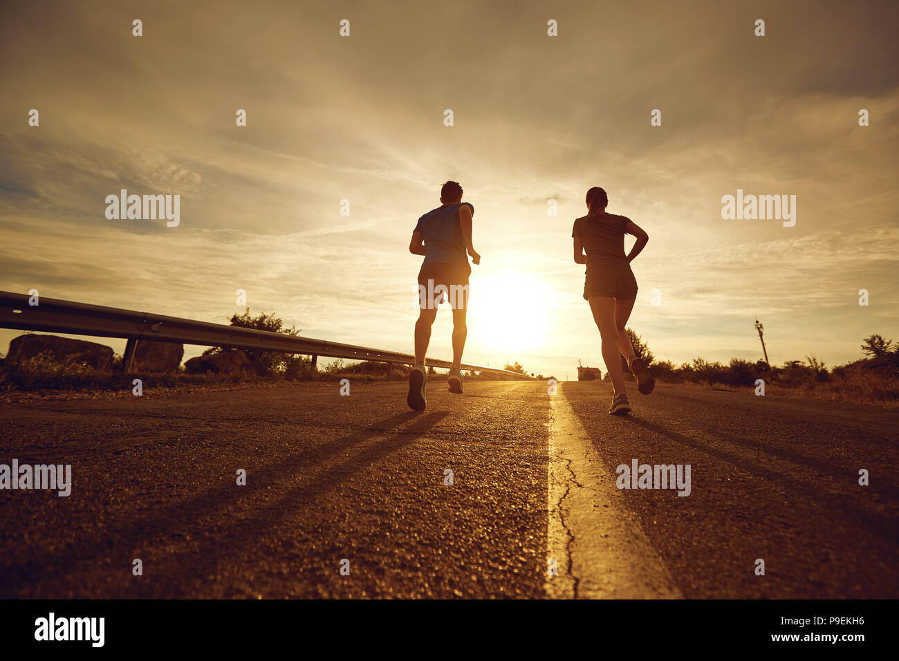 A guy and a girl jog along the road  in nature.  Stock Photo