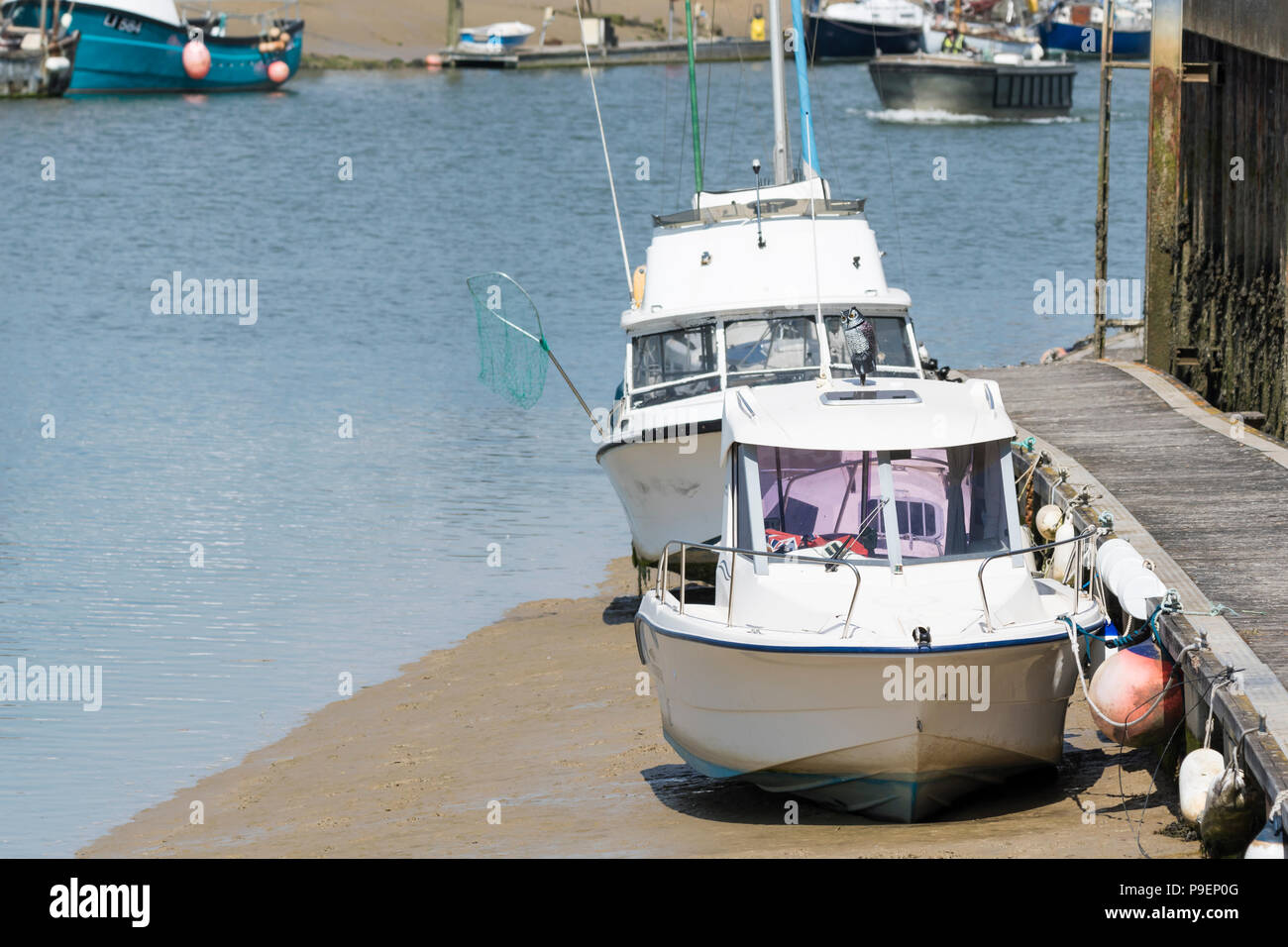 Small pleasure boats moored up on a river at low tide, resting on sand banks on the River Arun in Littlehampton, West Sussex, England, UK. Stock Photo