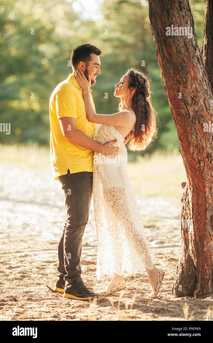 Young enamored couple hugs in forest against background of tree. Stock Photo