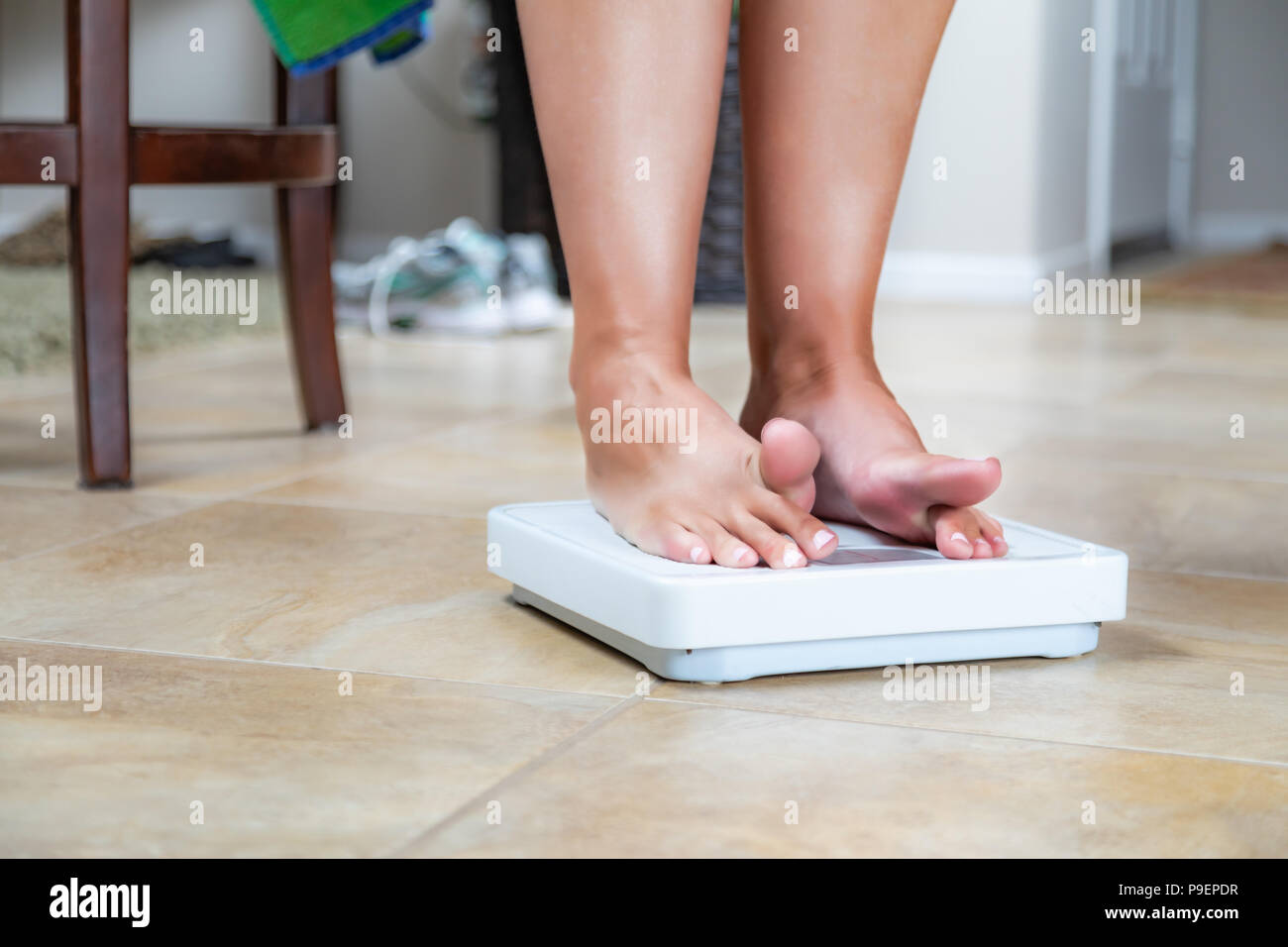 https://c8.alamy.com/comp/P9EPDR/woman-standing-on-scale-at-home-reluctantly-viewing-weight-P9EPDR.jpg