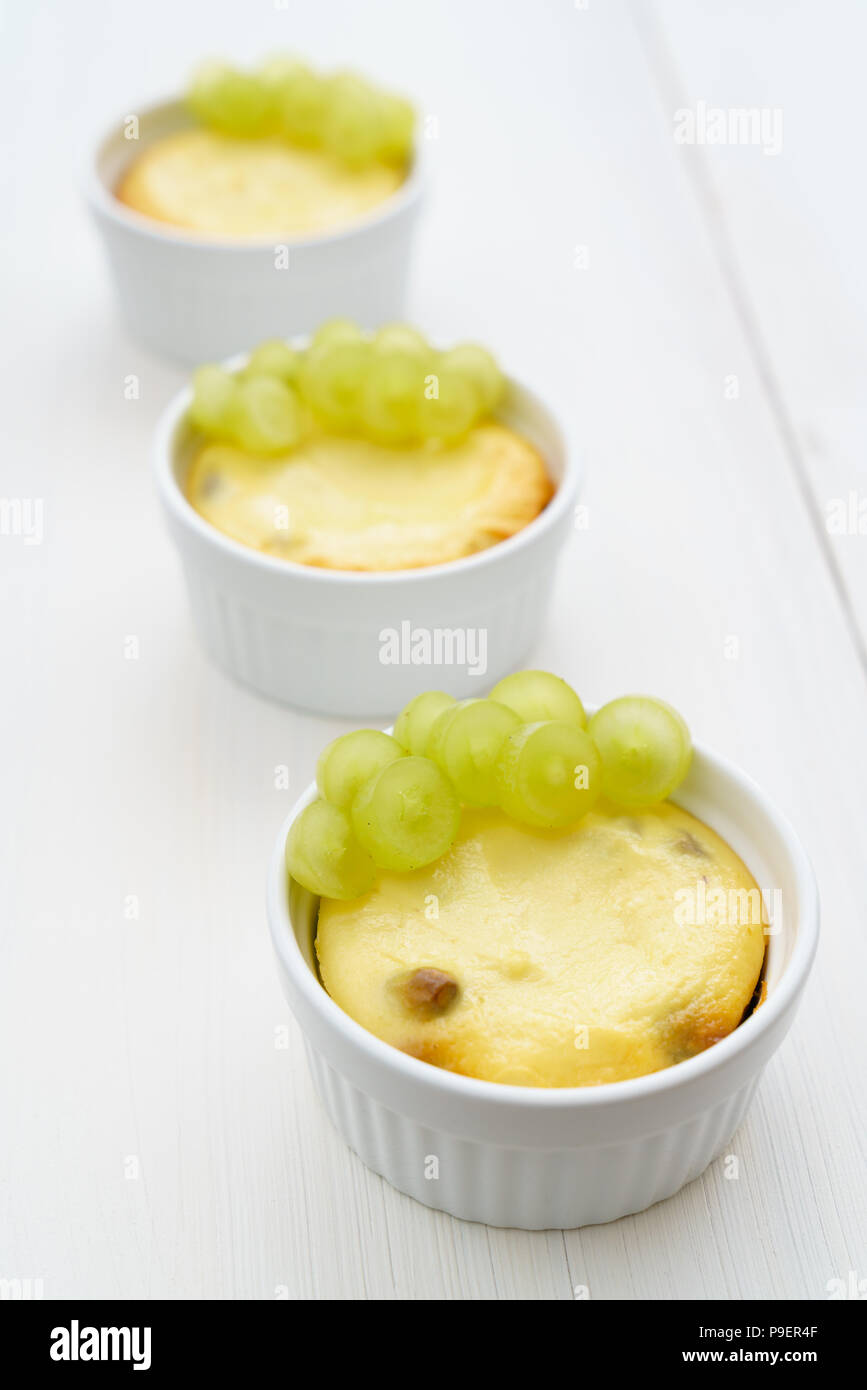 Mini zapekankas (baked quark dessert) with raisins and fresh grape. White wooden table, high resolution Stock Photo