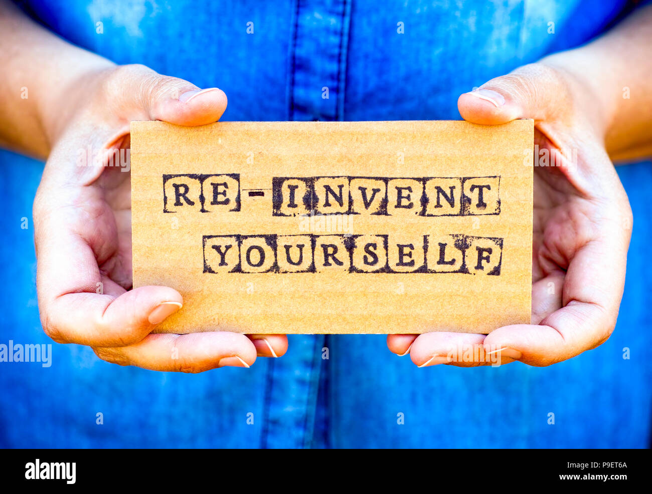 Woman hand holding cardboard card with words Re-Invent Yourself made by ...