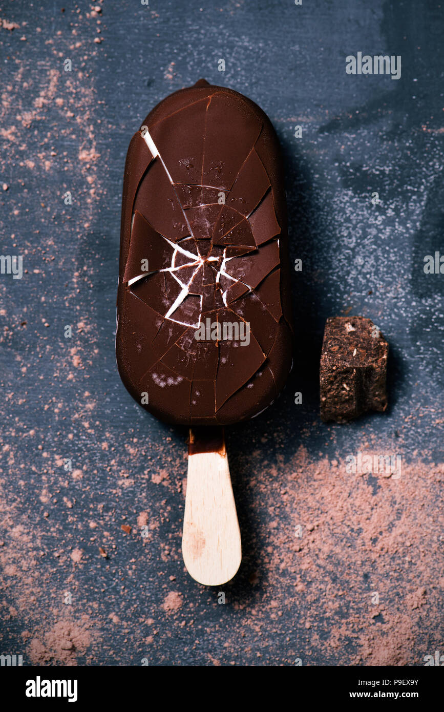 high angle view of a chocolate ice cream bar on a dark rustic wooden table sprinkled with cocoa powder Stock Photo