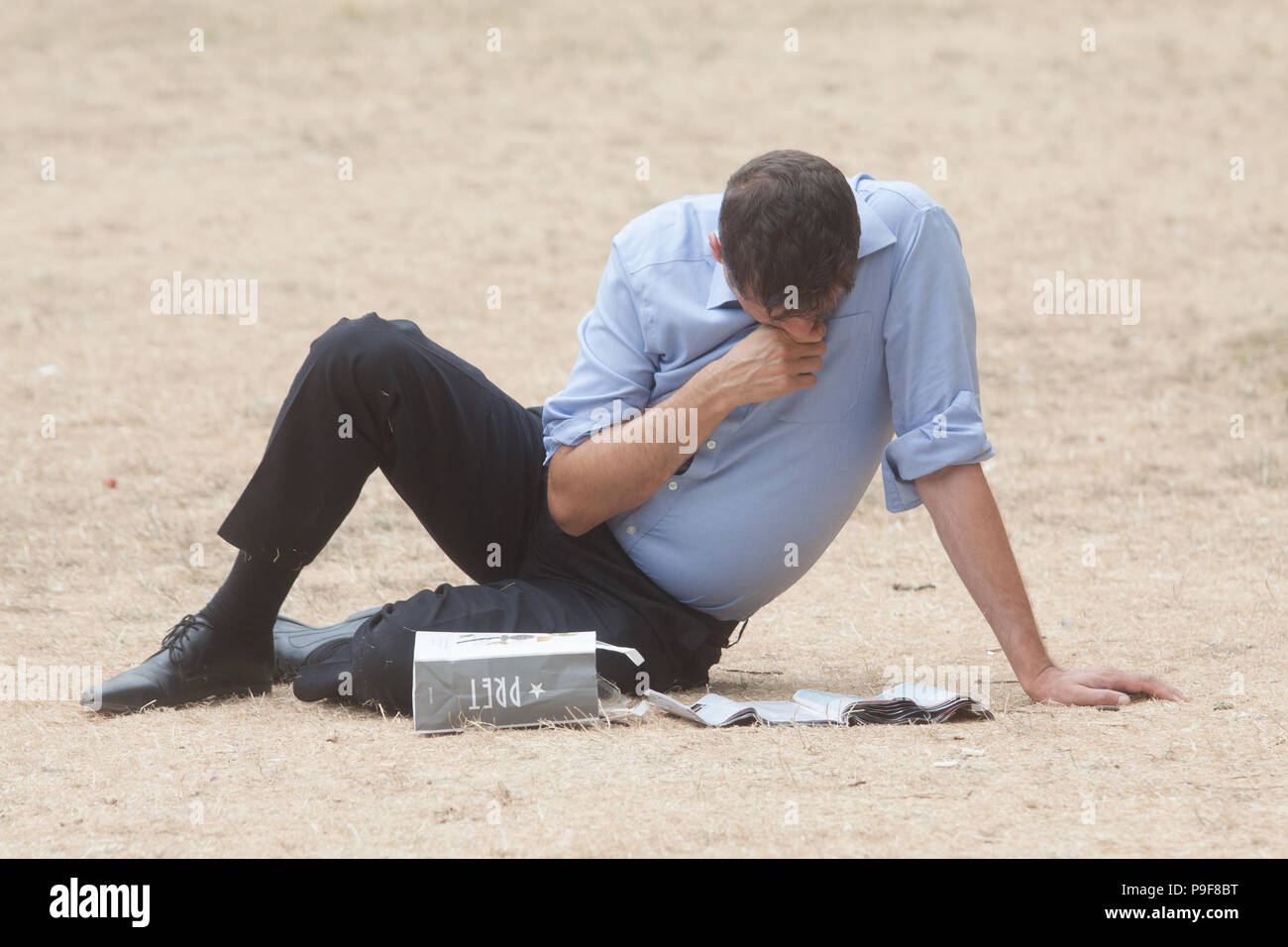 London UK. 18th July 2018 . People relax on a hot and humid day on the parched yellow grass  in Saint James's Park London  caused by the summer heatwave and 42 consecutive days of sunshine . A hosepipe ban is due to be imposed  in northwest  England by United Utilities due to a water shortage and a lack of rainfall Credit: amer ghazzal/Alamy Live News Stock Photo