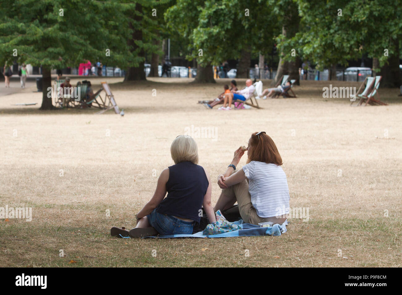 London UK. 18th July 2018 . People relax on a hot and humid day on the parched yellow grass  in Saint James's Park London  caused by the summer heatwave and 42 consecutive days of sunshine . A hosepipe ban is due to be imposed  in northwest  England by United Utilities due to a water shortage and a lack of rainfall Credit: amer ghazzal/Alamy Live News Stock Photo