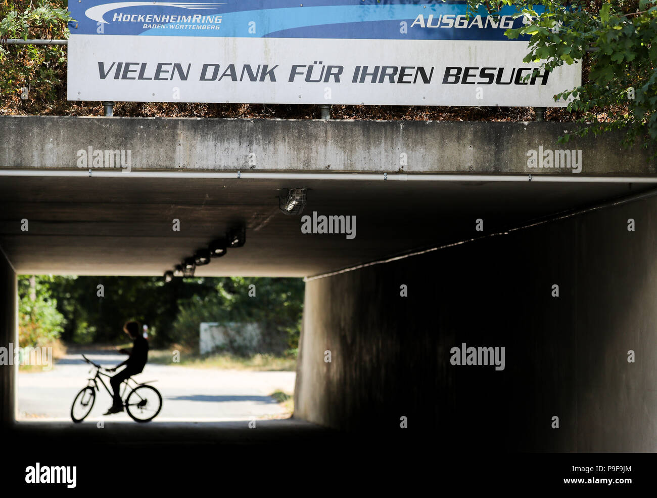 Hockenheim, Germany. 18th July, 2018. A cycylist going through a tunnel with a sign on it stating 'Vielen Dank fuer Ihren Besuch' (lit. many thanks for your visit). Germany's biggest prize is taking place on the Hockenheimring on the 22 July 2018. Due to ongoing discussions regarding finance, further Formula 1 races in Germany are being questioned. The contract with the Hockenheimring is expiring after this Grand Prix. There is no race planned for 2019. It is doubtful if there will be one in 2020. Credit: Jan Woitas/dpa-Zentralbild/dpa/Alamy Live News Stock Photo