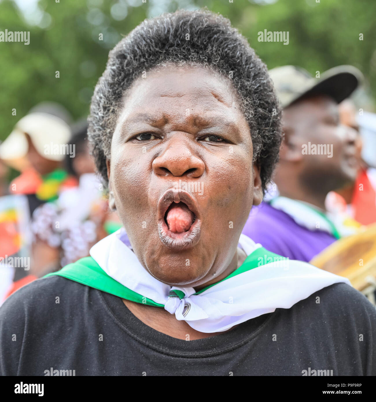 Parliament Square, Westminster, London, 18th July 2018. A woman sings in native tongue and performs an ululation, a high pitched trill of the tongue typical of traditional African singing. Protesters and activists demonstrate for various causes related to a free Zimbabwe, including fair elections, and a stop of forced removals of Zimbabweans from the UK. General elections are due to be held in Zimbabwe at the end of July. Credit: Imageplotter News and Sports/Alamy Live News Stock Photo